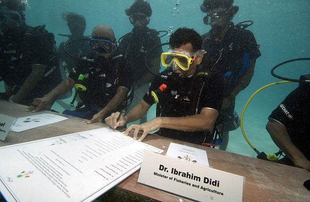 Maldivian Minister of Fisheries and Agriculture Ibrahim Didi signs a document calling on all countries to cut down their carbon dioxide emissions ahead of a major U.N. climate change conference in December in Copenhagen, in Girifushi, Maldives, Saturday, Oct. 17, 2009. Government ministers in scuba gear held an underwater meeting of the Maldives' Cabinet to highlight the threat global warming poses to the lowest-lying nation on earth. Maldivian President Mohammed Nasheed led Saturday's meeting around a table on the sea floor, 20 feet (6 meters) below the surface, with ministers communicating using white boards and hand signals. (AP Photo/Mohammed Seeneen)